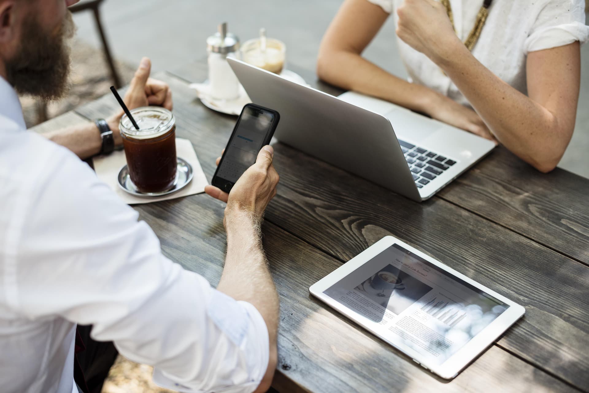 Two people meeting at a cafe table with a laptop, phone, and coffee
